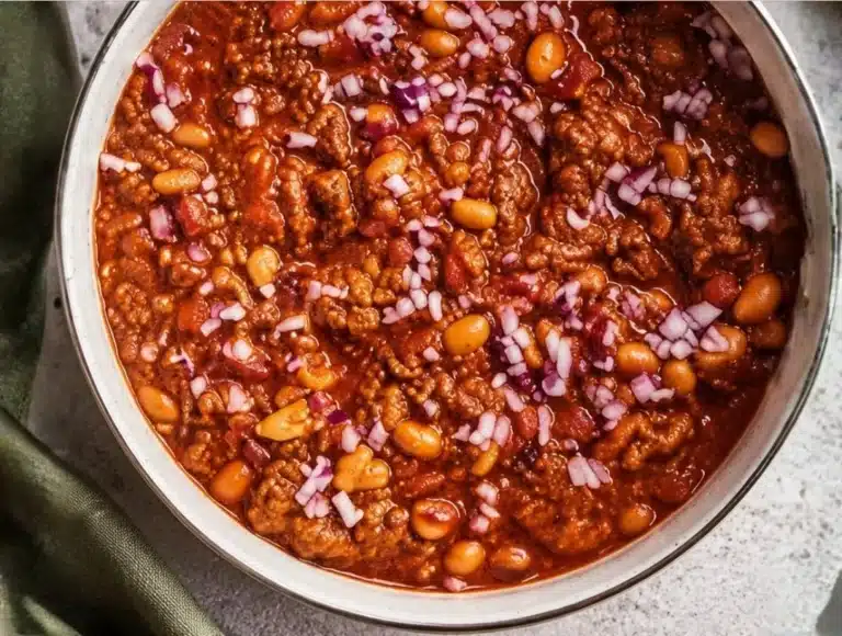 Delicious bowl of secret chili recipe topped with cheese and herbs