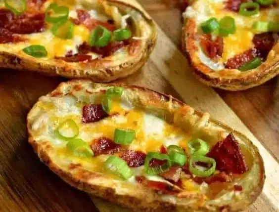 Crispy potato skins topped with bacon and green onions served on a platter.