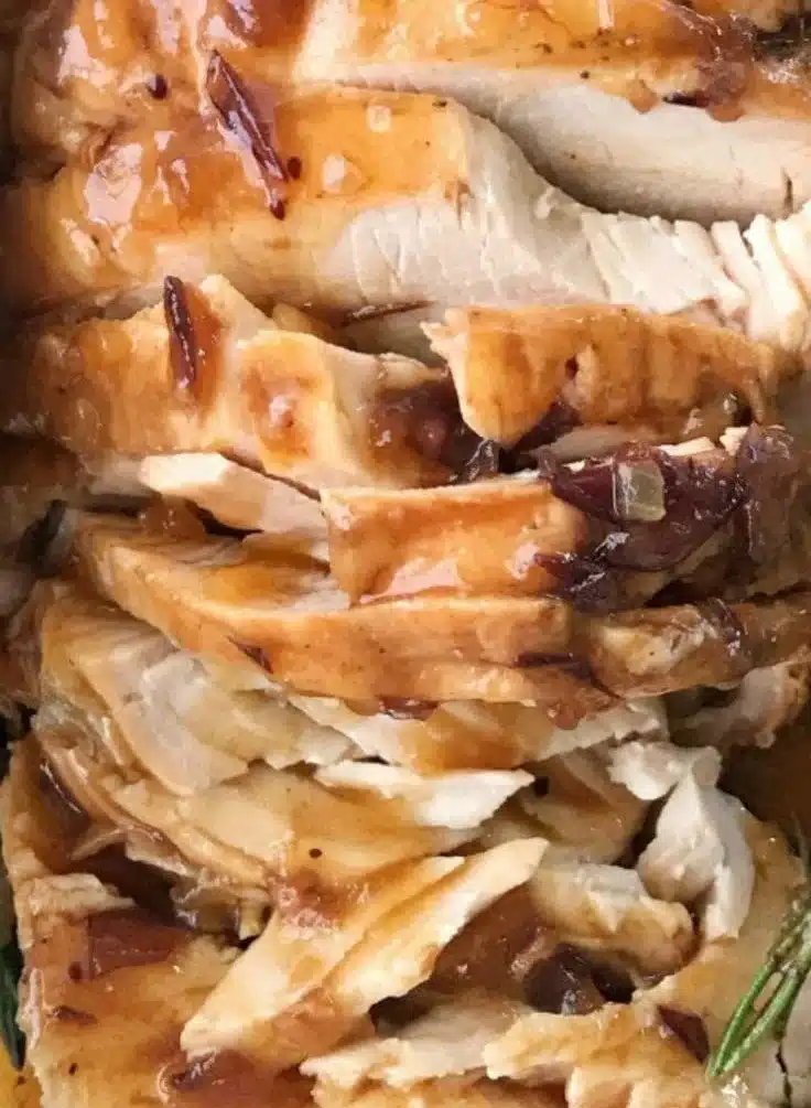 Crockpot turkey breast served with rich cranberry gravy on a festive table.