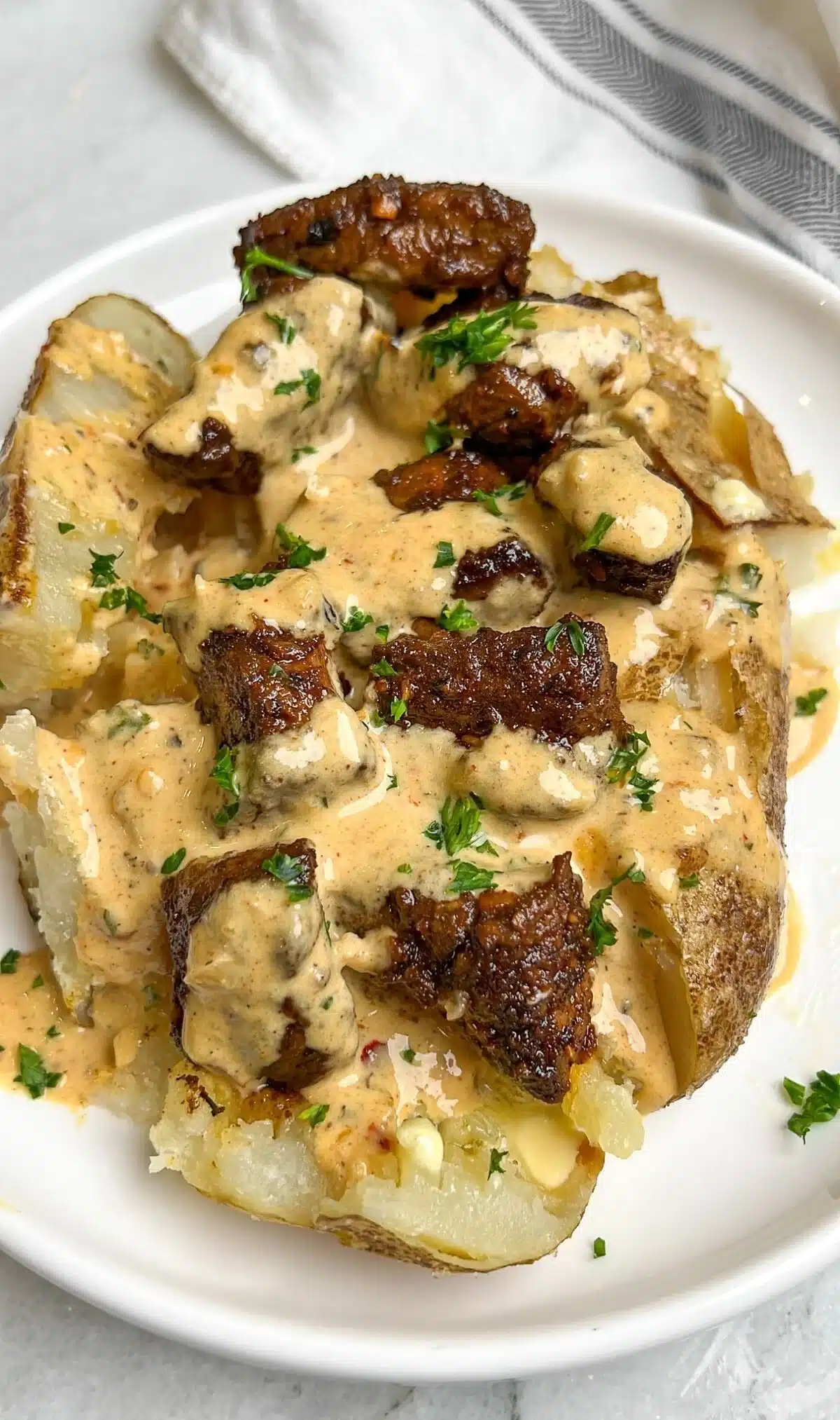 Loaded baked potato topped with steak bites and garnished with chives