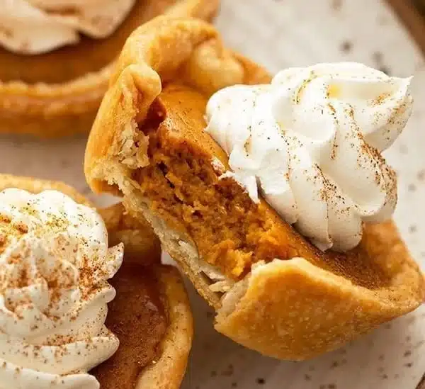 Mini pumpkin pie dessert served on a plate, garnished with whipped cream