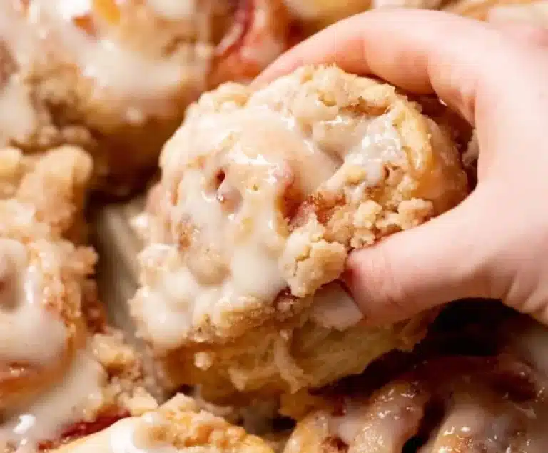Peach cobbler-style cinnamon rolls with crumb streusel topping on a plate