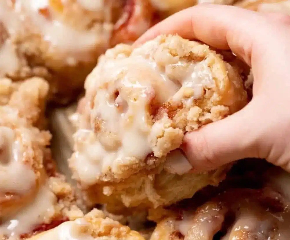 Peach cobbler-style cinnamon rolls with crumb streusel topping on a plate