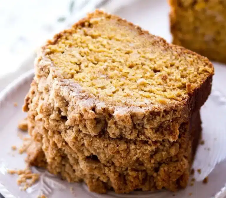 Sliced pumpkin bread with crumb topping on a wooden board