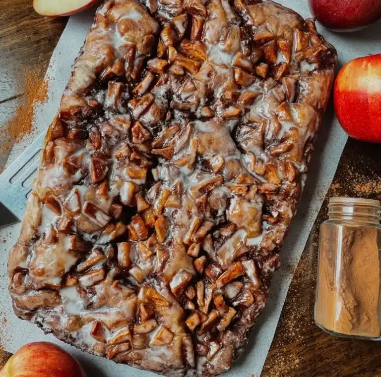 Freshly baked sourdough apple fritter focaccia loaf on a wooden table.